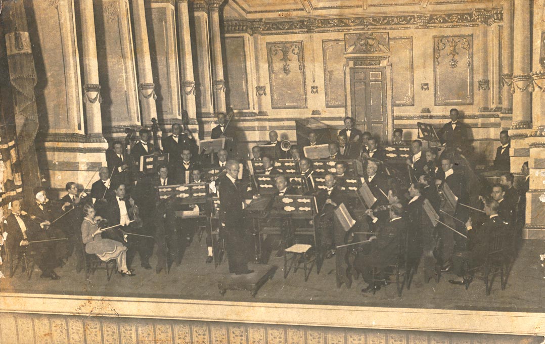 A photo of the symphonic orchestra of the Sociedade Musical Porto-Alegrense, founded by Alexandre Gnattali, being conducted by the great conductor Francisco Braga, on a visit to the city of Porto Alegre, capital of the state of Rio Grande do Sul, around 1928. In the photo are, besides Radamés (viola), members of his family, such as his cousin and violin teacher Olga Fossati (spalla), his uncle Camillo (viola), his cousin Pascoal (violin), and his father Alexandre (bassoon).